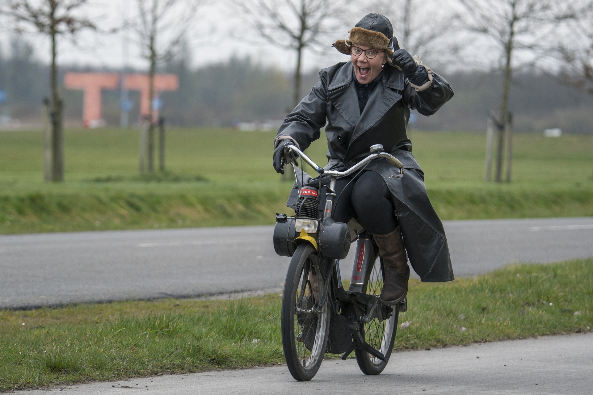 An elderly woman on a scooter giving a thumbs up.